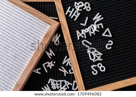 Black and white wooden lightboxes with scattered letters from top. Copy space.