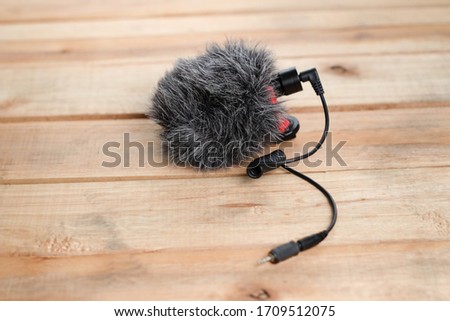 A directional compact external microphone for cameras and SLR cameras, with anti-vibration mount and synthetic fluffy windproof,External microphone on wooden table
