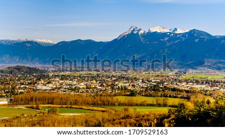 The sun setting over Cheam Peak, Lady Peak and Knight Peak in the Cascade Mountains and over the town of Chilliwack in the Fraser Valley of British Columbia, Canada Royalty-Free Stock Photo #1709529163