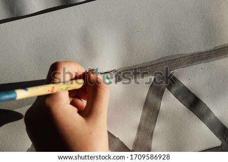 Close up of a young girl's hand painting a picture with watercolours