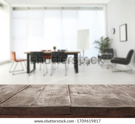 Empty wooden surface and blurred view of modern office interior, closeup. Space for text 