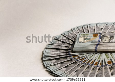 A fan of hundred-dollar bills on a light background. Free space for text.