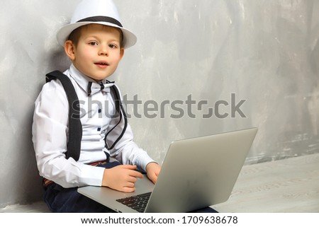 Portrait of Genius. Young boy working on the computer sitting On the floor. Studying. Online learning remotely. Distant school. Distance education. Online courses and knowledge.