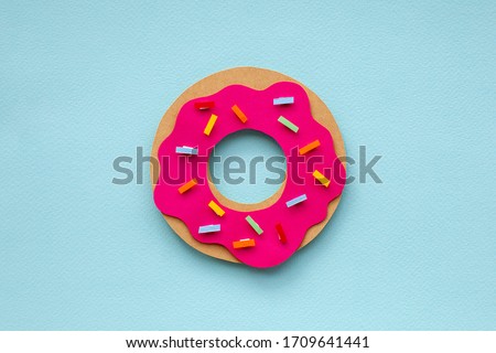 Colorful paper cutout strawberry donut on blue background. Colorful sprinkling. Handmade art work for your birthday card. 