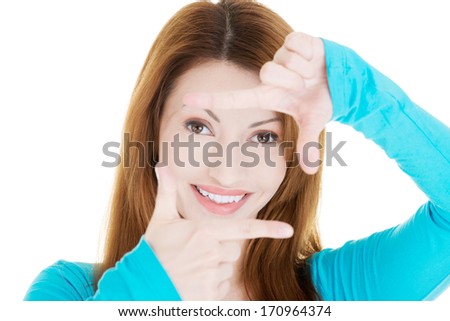 Smiling woman wearing blue blouse is showing frame by hands. Happy girl with face in frame of palms. Isolated on white background. 