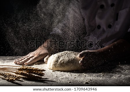 White flour flying into air as pastry chef in white suit slams ball dough on white powder covered table. concept of nature, Italy, food, diet and bio. Royalty-Free Stock Photo #1709643946
