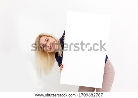 Girl and blank canvas. Copy space on canvas board for image or message. Young woman looking at mockup poster and standing over grey background.