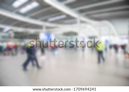 Abstract blurred passengers inside large modern railway terminal concourse