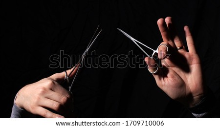 Hands hold the scissors. Man hand. Dark background 