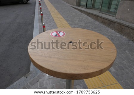 Round brown street table with the sign alcohol prohibited and yellow line on the gray stone sidewalk