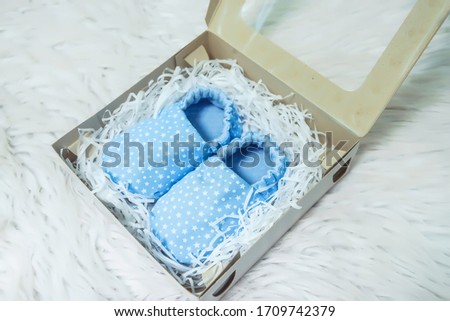 Gently blue booties for newborns in a gift box. lightweight decorative boots for infants up to 1 year old. clothes for babies. small children's shoes made of white polka dot fabric.