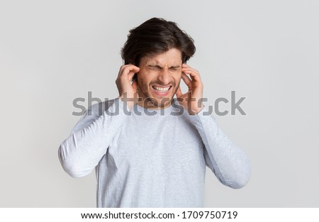 Ear pain concept. Man grimaces and touches ears, free space Royalty-Free Stock Photo #1709750719