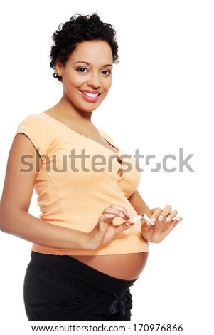 Pregnant woman breaking a cigarette - stop smoking concept 