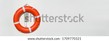 Orange life belt hanging on white wall, nautical panoramic background Royalty-Free Stock Photo #1709770321
