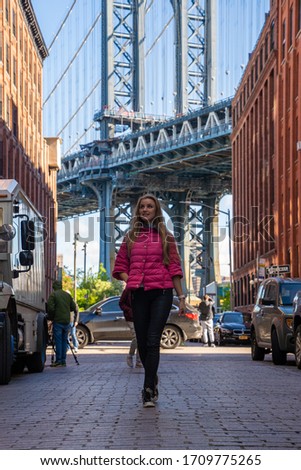 Young beautiful lady walking down the Washington street, in Brooklyn with a Manhattan bridge in the background.
