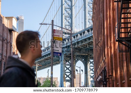 Young man standing on the Washington street, in Brooklyn with a Manhattan bridge in the background.