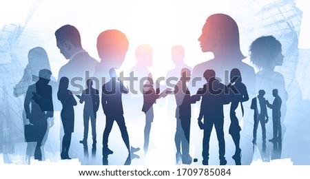 Business meeting and teamwork concept. Silhouettes of diverse business people with double exposure of blurry abstract cityscape. Toned image