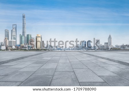 empty tiled ground, and skyscrapers in the city, with blue sky and cloud.