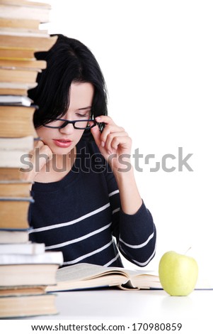 Young student woman with books studying at the desk, isolated on white background 