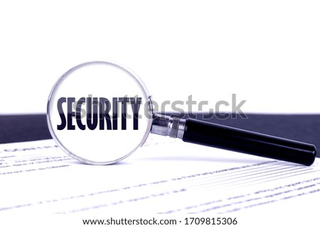 Magnifying glass with text concept word Security on a dark table and a light background.