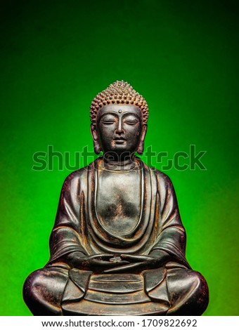A small replica statue of The Buddha with a green background.  Green symbolizing cleanliness and purity from contamination.