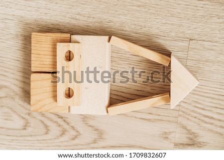 in the foreground a toy rocket made of wooden beige cubes in the background a wooden beige floor