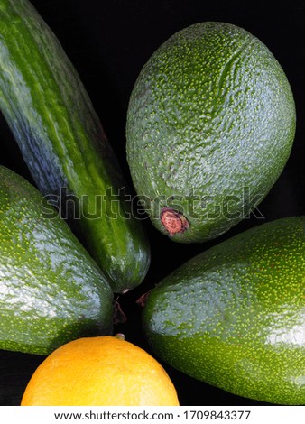 Isolated lemon, cucumber, avocado on a black background closeup, The perfect combination of products for a vegetarian salad. Bright vertical picture with ripe vegetables for design  artwork.