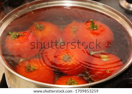 Red blanched tomatoes in a hot water metal pot. tomatoes boil in hot water Royalty-Free Stock Photo #1709853259