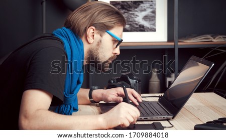 Portrait of male photographer processing retouching images using laptop and graphic drawing tablet