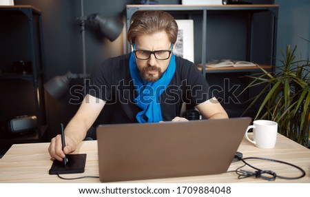 Front view of professional photographer working in photo editing app using laptop and drawing tablet