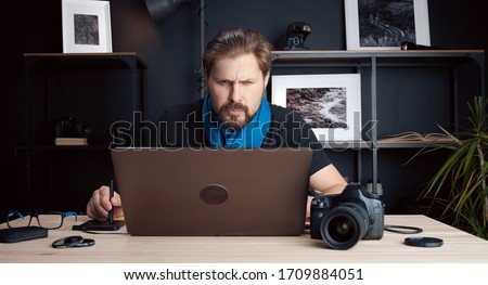 Portrait of photographer processing retouching images using laptop and graphic drawing tablet