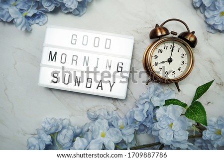 Good Morning Sunday word in light box with Flowers Decoration on wooden background