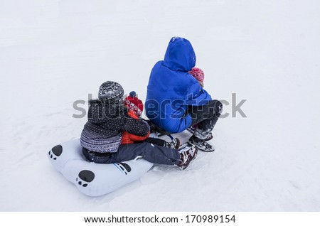 Father and three kids on a sled.