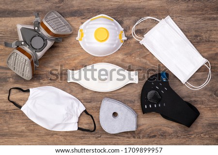 Different protective masks on wooden background, top view Royalty-Free Stock Photo #1709899957