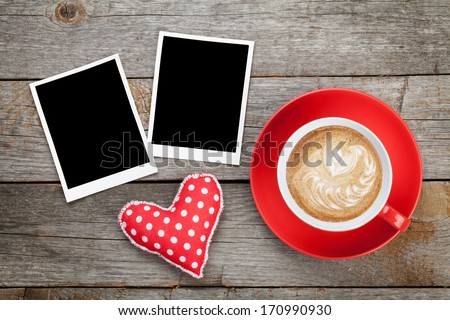Two photo frames over wooden background with red coffee cup and heart toy