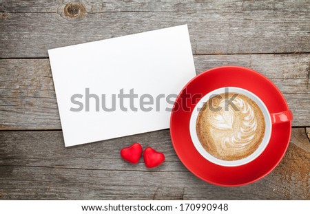 Blank valentines greeting card and red coffee cup on wooden background