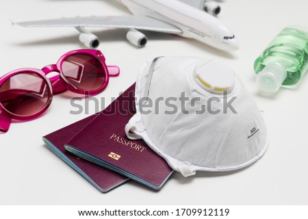 Travelling during the coronavirus outbreak. Passport with face mask, sunglasses and hand sanitizer gel. Travel and Holiday concept corona virus epidemic.  Royalty-Free Stock Photo #1709912119