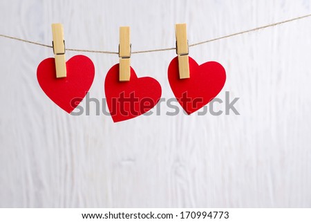 Three love hearts hanging on wooden texture background, valentines day card concept