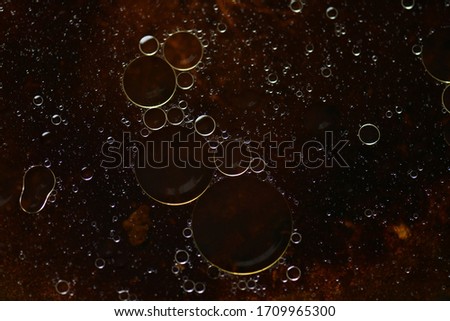 Picture of vegetable oil bubbles with bubbles of various sizes floating on the water surface, dark tones