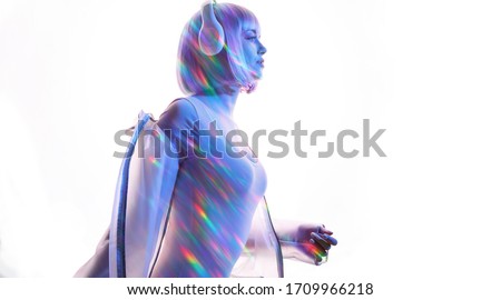 Beautiful woman with purple hair in futuristic costume over white background. Blue and violet neon light. Portrait of young girl in modern headphones listening music. Free space for text.