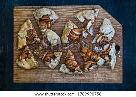 Apple galette - pie sliced ​​into pieces on a wooden dark background. Copy space, flat lay.