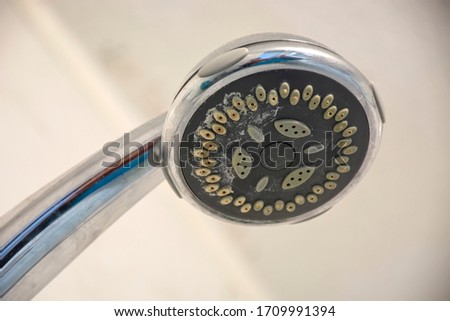Dirty chrome shower head with limescale that should be cleaned. Calcified shower due to hard water. Calcium mineral buildup. Royalty-Free Stock Photo #1709991394