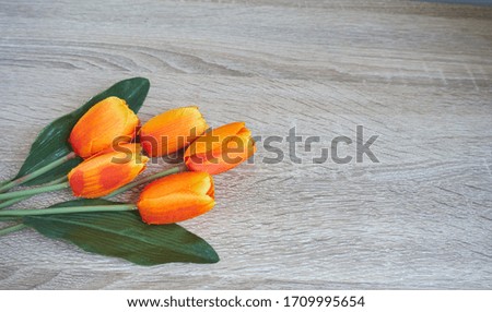 Beautiful orange tulips on woonden background, top view.