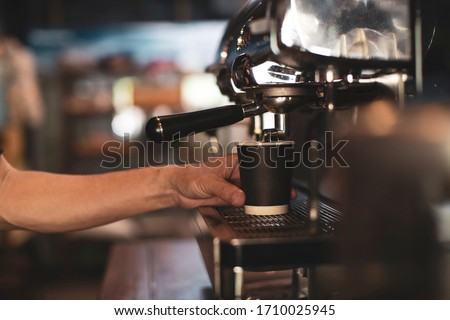 Coffee extraction on espresso machine in the red cup. Close-up of espresso pouring from coffee machine.