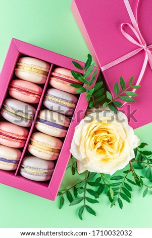 Colorful macaroons and flowers. Sweet macarons in gift box. Top view
