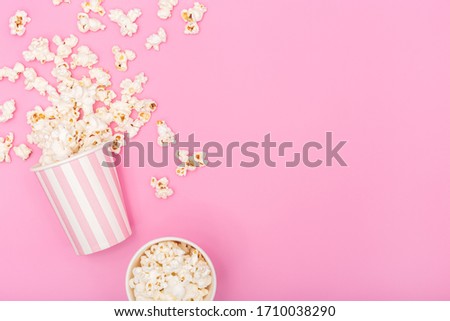 Popcorn bucket on pink background. Movie or TV background. Top view Copy space