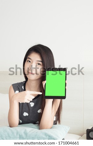 Young Asian woman show or display and pointing tablet with green screen