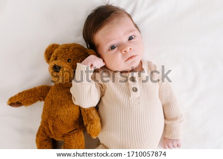 Baby with a bear toy on the bed top view