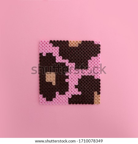 Square coaster with flowers made with plastic hama beads, top view on pink background