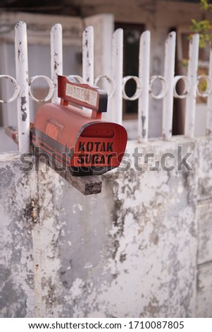 red mailbox, it says Kotak Surat in Indonesian which means mailbox